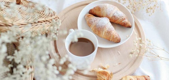 Cup of coffee with croissants on a wooden tray with dried flower © Rasa - stock.adobe.com
